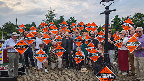 A photo of a large group of people holding up orange "Winning Here" signs