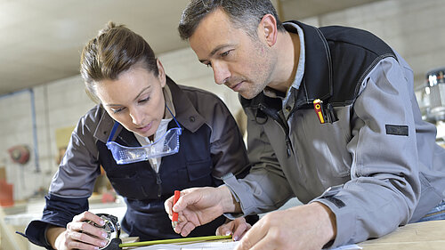 A carpenter teaching a trainee.