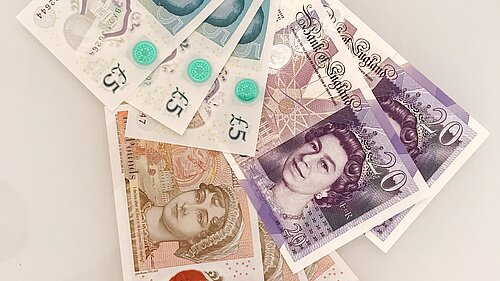 Seven pound coins on top of a ten pound note.